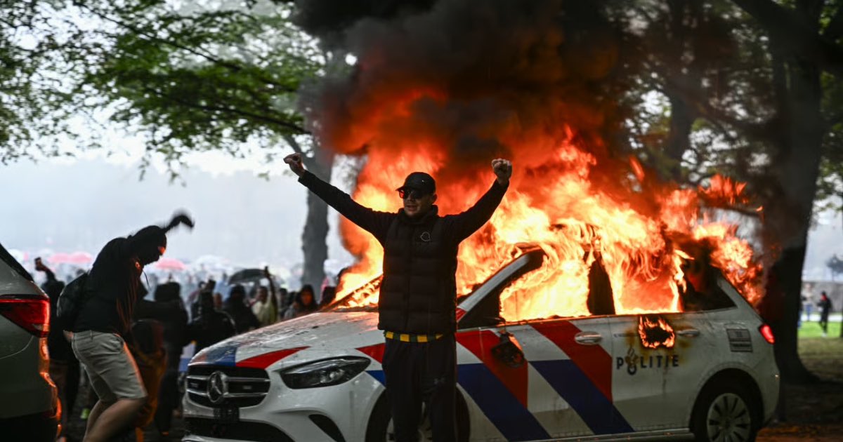 A police car burns during clashes at a demonstration in The Hague