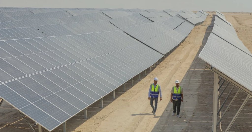 Workers walk between solar panels at a newly opened industrial-scale solar power plant in Karbala, Iraq, Wednesday, Sept. 17, 2025. (AP Photo/Anmar Khalil)