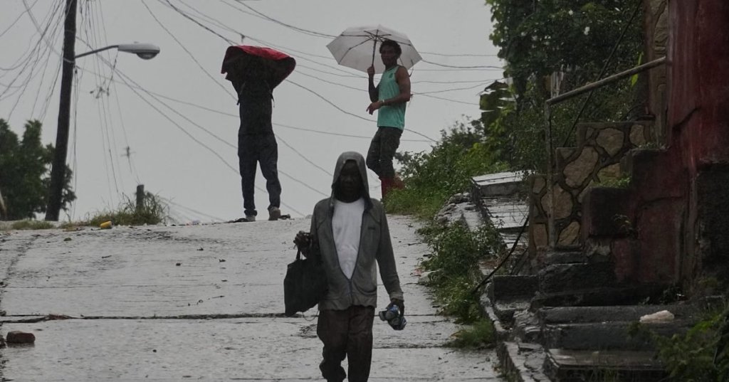 People walk under the rain before the arrival of Hurricane Melissa in Santiago de Cuba, Tuesday, Oct. 28, 2025. (AP Photo/Ramón Espinosa) - Copyright AP Photo