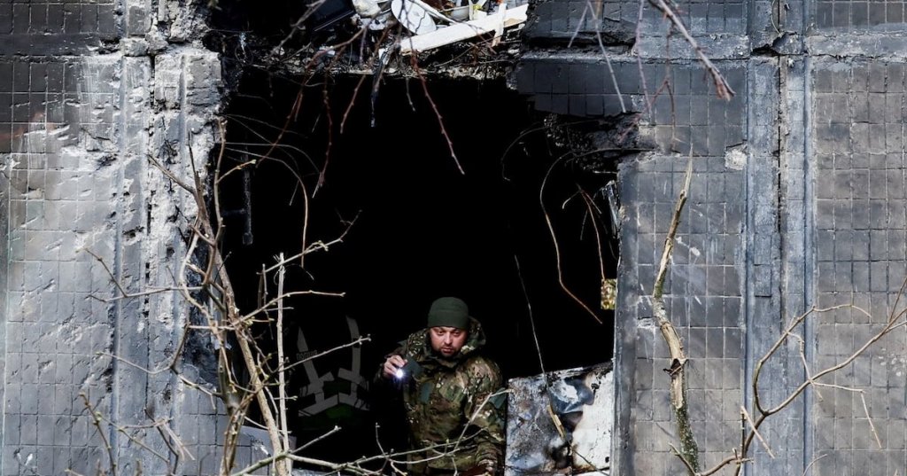 An investigator looks through the window of an apartment building damaged during an overnight Russian drone and missile strike, amid Russia's attack on Ukraine, in Kyiv, Ukraine, November 14, 2025. REUTERS/Thomas Peter