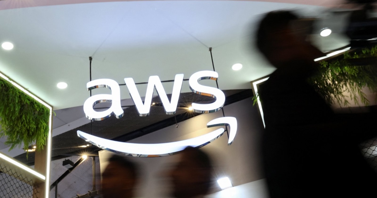 People walk past the logo of Amazon Web Services (AWS) at its exhibitor stall at the India Mobile Congress 2025 at Yashobhoomi, a convention and expo center, New Delhi, India, Oct. 8, 2025. (Reuters Photo)