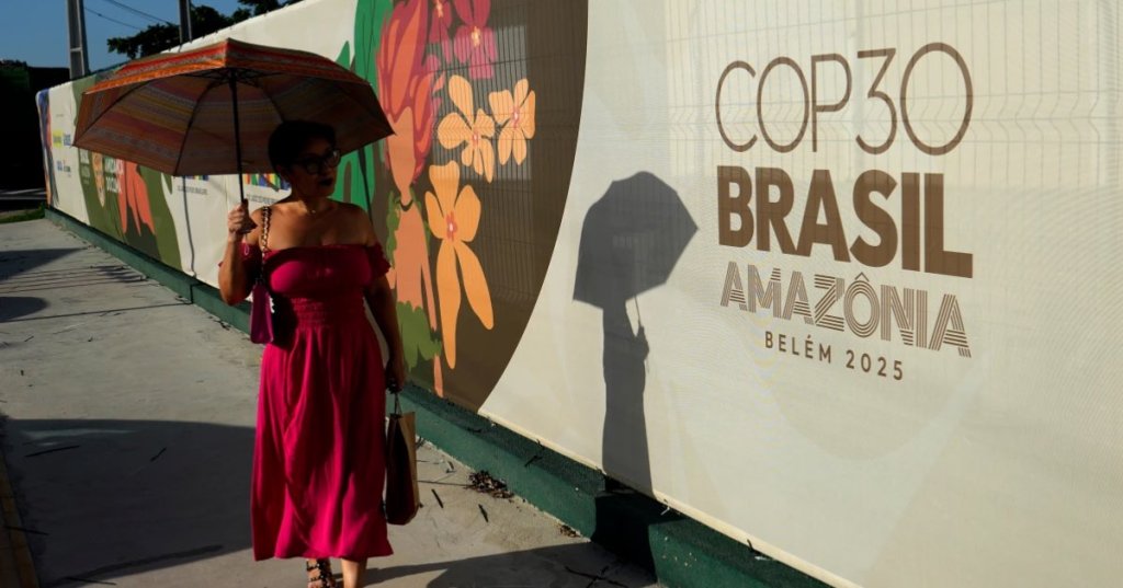 A woman walks past a sign for the COP30 U.N. Climate Summit, in Belem, Para state, Brazil, Tuesday, November 4, 2025.(AP Photo/Eraldo Peres)