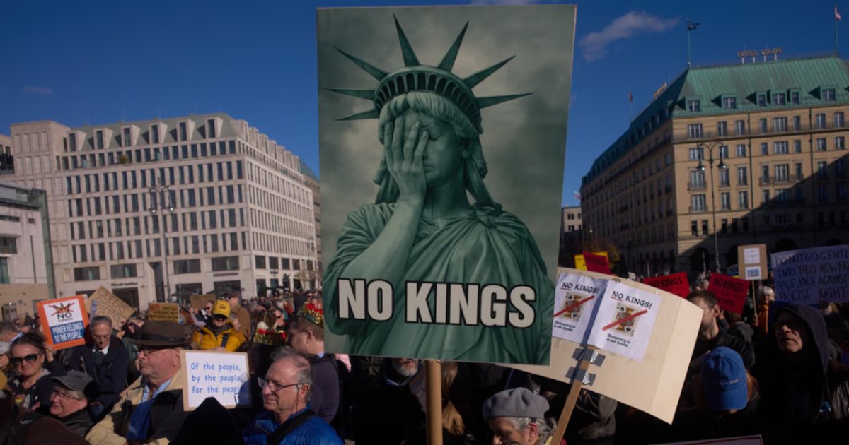 A woman displays a "No Kings" sign as she participates in a pro-democracy, anti-Trump protest outside the US embassy at the Pariser Platz square in Berlin, Germany Saturday, Oct. 18, 2025.(AP Photo/Markus Schreiber)