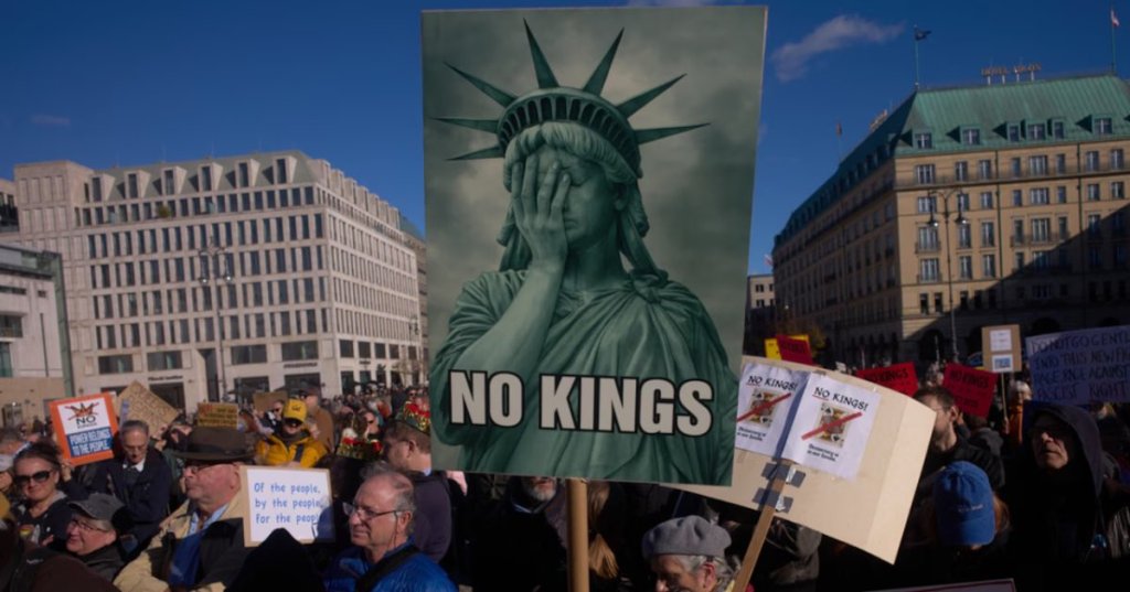 A woman displays a "No Kings" sign as she participates in a pro-democracy, anti-Trump protest outside the US embassy at the Pariser Platz square in Berlin, Germany Saturday, Oct. 18, 2025.(AP Photo/Markus Schreiber)
