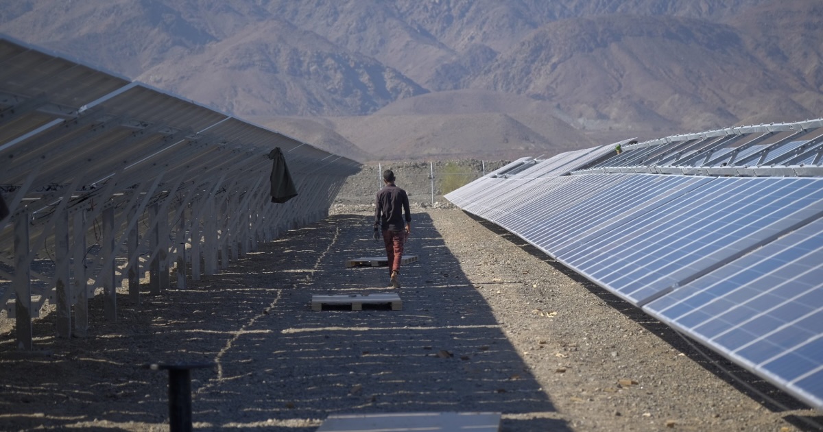 An Iranian worker walks past solar panels in a solar power farm in the Qaleh Ganj area about 1372Km (853 Miles) southeast of Tehran in Kerman province. (Photo by Morteza NikoubazlNurPhoto via AP)
