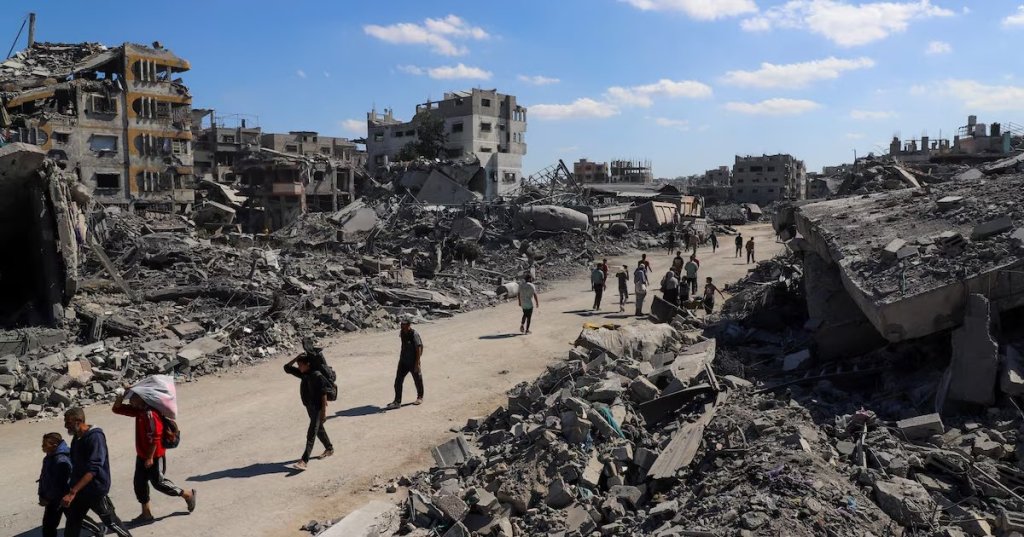 Palestinians walk past the rubble of destroyed buildings, amid a ceasefire between Israel and Hamas, in Gaza City, October 14, 2025. REUTERS/Ebrahim Hajja