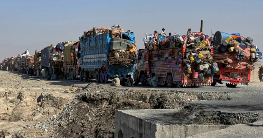Afghan refugees sit beside trucks loaded with their belongings as they wait their turn to leave for their homeland through a border crossing point which partially opens following Oct. 19 ceasefire, on the outskirts of Chaman, a border town on the Pakistan Afghan border, Wednesday, Oct. 29, 2025. (AP Photo/H. Achakzai)
