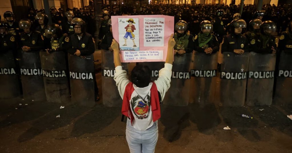 A demonstrator holds a poster as police officers stand guard during a protest against the government of Peru's President Dina Boluarte after Congress approved a partial withdrawal of private pension savings, a measure which could leave millions of Peruvians without retirement funds, in Lima, Peru, September 20, 2025. REUTERS/Sebastian Castaneda/File Photo