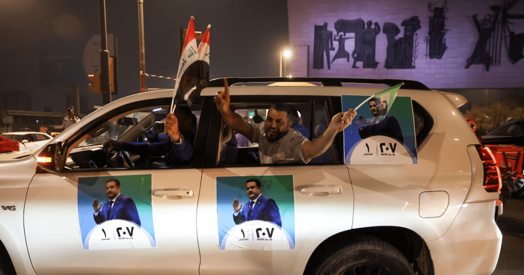 People drive in a car with election posters featuring current Prime Minister Mohammed Shia' al-Sudani, as supporters of the Reconstruction and Development Coalition celebrate after preliminary election results were announced in Baghdad, Iraq, November 12, 2025. REUTERS/Ahmed Saad