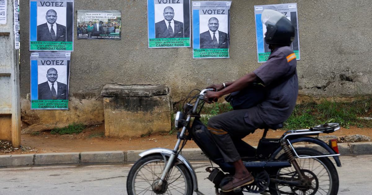 A motorist rides past campaign posters of Jean-Louis Billon, presidential candidate of the CODE (Democratic Congress), ahead of Ivory Coast's presidential election