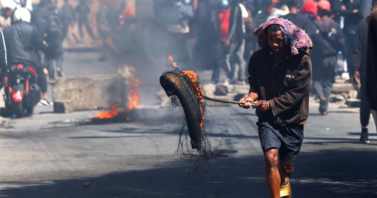 A protester runs while holding a burning tyre to barricade a road during a nationwide youth-led demonstration over frequent power outages and water shortages, in Antananarivo, Madagascar, October 6, 2025. REUTERS/Siphiwe Sibeko