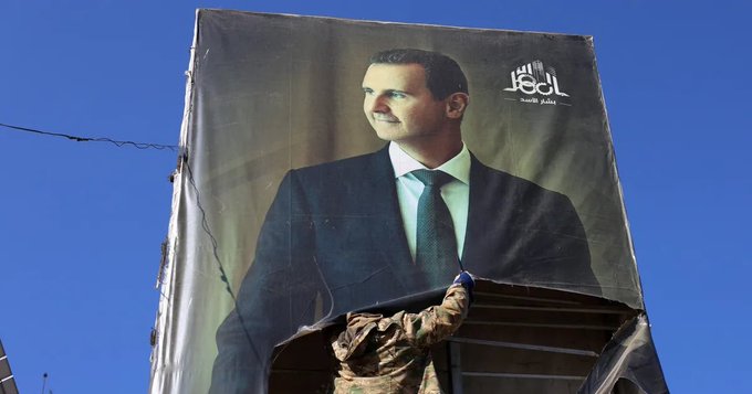 An anti-government fighter tears down a portrait of Bashar Al-Assad in Aleppo.Photographer: Mohammed Al-Rifai/Getty Images
